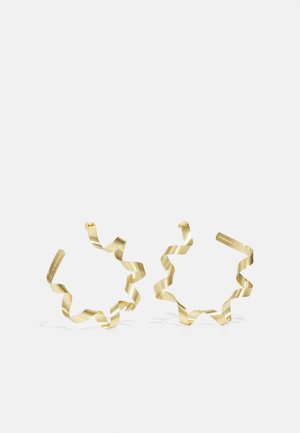 Boucles d'oreilles en spirale dorées au design ondulé, avec une finition métallique lisse et une forme ouverte. Légères et minimalistes.