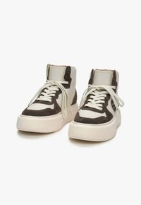 Vysoké tenisky s béžovým koženým a tmavě hnědým semišovým svrškem, kulatou špičkou, bílou gumovou podrážkou a béžovými tkaničkami.