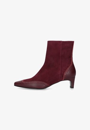Bottes chelsea bordeaux en daim avec un bout pointu, des détails de brogue décoratifs et un talon bas. Accents en cuir lisse sur les côtés.