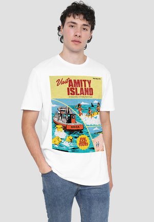 White short-sleeve t-shirt featuring a colorful graphic print of a boat labeled "ORCA" and vintage-style text about Amity Island.