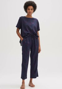 Navy tweedelige outfit met een losvallende top met korte mouwen en een pantalon met patroon, voorzien van een elastische tailleband en een trekkoorddetail.