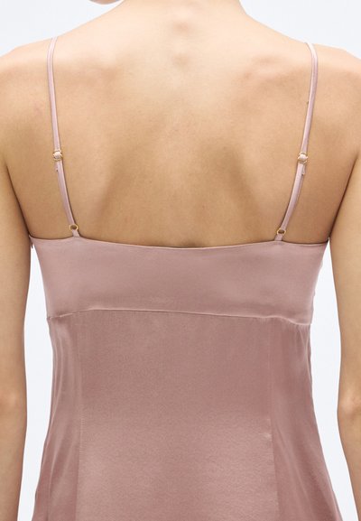 Rožinės spalvos satino palaidinė su plonomis petnešėlėmis, papuošta auksiniais apskritais metaliniais elementais. Lygus audinys ir paprastas dizainas su tiesiu kirpimu nugaroje.