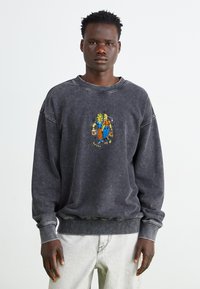 Donkergrijze sweatshirt van zachte stof. Bevat een ronde hals, geribde boorden en kleurrijke cartoonborduursels aan de voorkant.