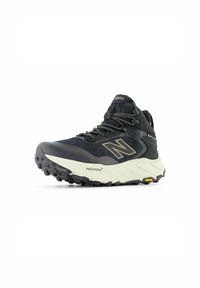 Scarpa sportiva nera con tomaia in mesh traspirante, suola Vibram e intersuola Fresh Foam. Presenta lacci riflettenti e un design alto alla caviglia.
