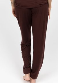 Bruine, lichtgewicht broeken met een gladde textuur, tapered leg ontwerp en opgerolde manchetten. Geen zichtbare zakken of afleidende details.