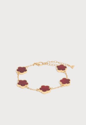 Pulsera de cadena dorada con cinco colgantes en forma de trébol de color rojo oscuro y un cierre ajustable sobre un fondo claro.