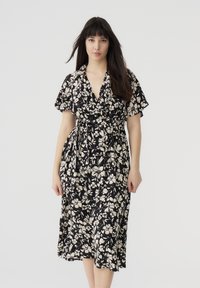 Abito a wrap floreale con maniche corte, tessuto nero con fiori bianchi, design al ginocchio e cintura con nodo in vita.