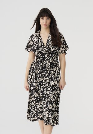 Abito a wrap floreale con maniche corte, tessuto nero con fiori bianchi, design al ginocchio e cintura con nodo in vita.