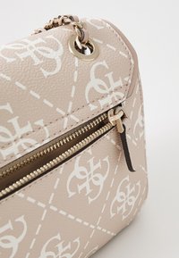 Borsa a tracolla in ecopelle beige con motivo logo bianco, zip dorata e dettaglio a catena sulla tracolla.