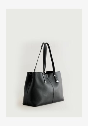 Sac en cuir noir avec une surface texturée, deux longues poignées et des accents matériels en argent minimalistes. Offre un design intérieur spacieux.