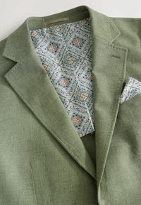 Grüner Blazer aus strukturierter Stoff; gemusterte hellblaue und florale Fütterung; mit passendem Taschenquadrat; strukturierte Revers.