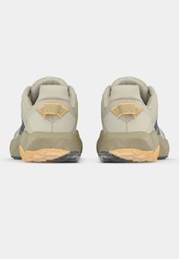 Pantofi sport de culoare neutră, cu partea superioară din plasă texturată, guler căptușit și accente galbene contrastante pe călcâi și talpă. Design al tălpii pentru tracțiune.