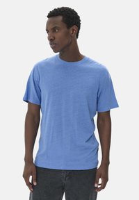 Ljusblå bomulls-t-shirt med korta ärmar, rund halsringning, avslappnad passform och subtil struktur. Matchat med mörkgrå byxor.