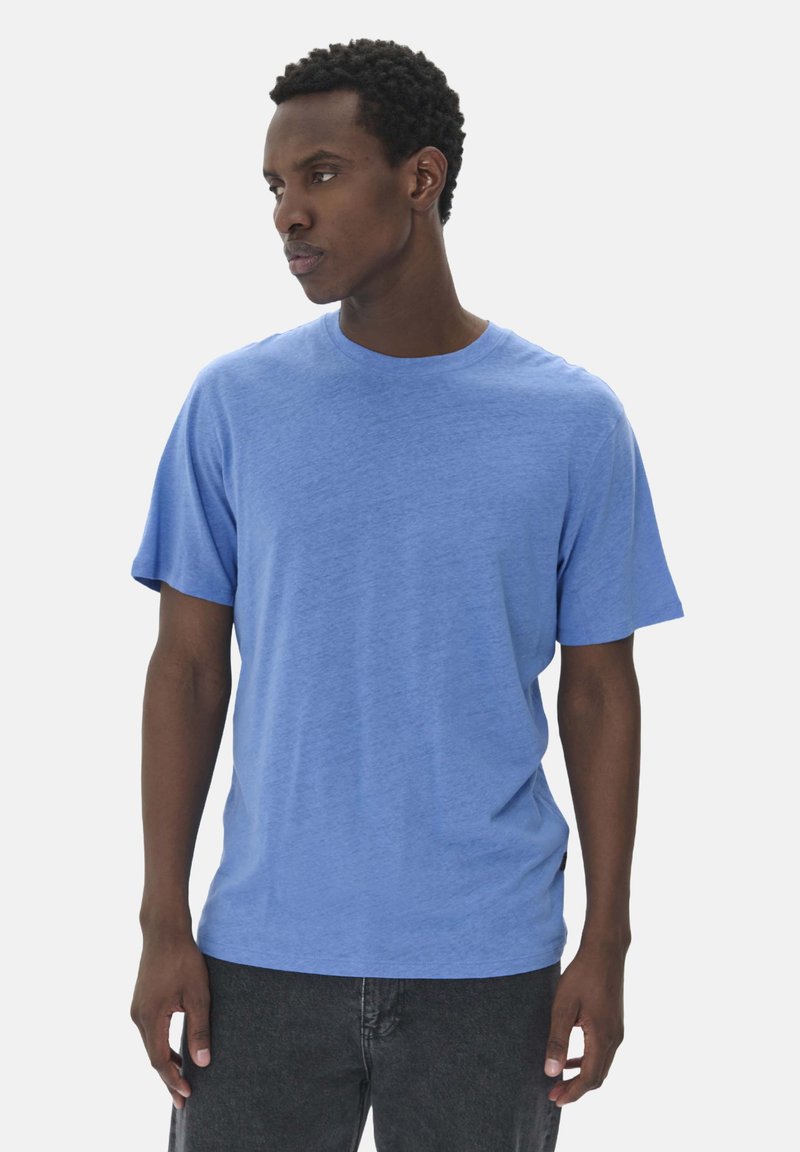 Ljusblå bomulls-t-shirt med korta ärmar, rund halsringning, avslappnad passform och subtil struktur. Matchat med mörkgrå byxor.