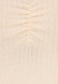 Beige bordás kötött anyag, függőleges csíkokkal és finom textúrával, középen redőzött. Puha és rugalmas anyag.