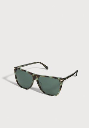 Lunettes de soleil écaille avec des verres vert foncé et des détails dorés, présentées de biais sur un fond clair.