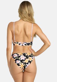 Čierny kvetinový bikini set s kvetinovým vzorom v pastelových farbách, tenkými ramienkami a spodnou časťou s miernym pokrytím a detailom značky.