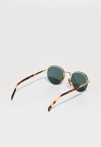 Ochelari de soare rotunzi cu lentile de culoare verde închis, ramă din metal cu ton de aur și brațe cu model țestoasă. Include tampoane pentru nas pentru confort.