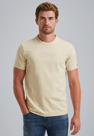 Beige T-Shirt mit kurzen Ärmeln und rundem Ausschnitt, versehen mit dem geprägten PME Legend Logo. Kombiniert mit Denim-Jeans, aus einem glatten Stoff gefertigt.