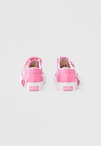 Ροζ και άσπρα αθλητικά παπούτσια με αυτοκόλλητο λουράκι, λείο συνθετικό υλικό, στρογγυλεμένη μύτη και στρογγυλεμένη φτέρνα, με λογότυπο στο πίσω μέρος.