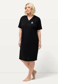 Svart nattsärk med korta ärmar, V-ringning och rynkad detaljer. Har en liten broderad design på bröstet. Slät tyg.