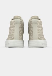 Ténis de cano alto bege com parte superior em tecido estampado, sola de borracha branca e painéis laterais elásticos para facilitar o uso.