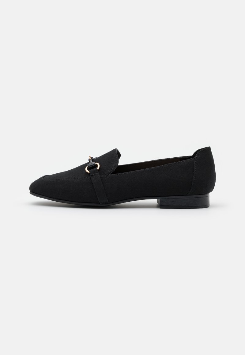 Mocassins en toile noire avec un bout arrondi, un petit talon bloc, et une bride décorative avec un accent doré. Texture lisse et design minimaliste.
