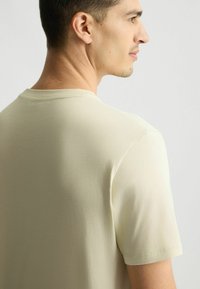 Hellbeige Rundhalsausschnitt-T-Shirt aus weicher Baumwolle, mit kurzen Ärmeln und einer lässigen Passform, mit einfarbigem Stofftextur und sauberen Nähten.