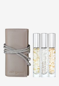 Leather case in soft taupe color with silver rope closure, containing three glass roller bottles of serum with gold flakes.