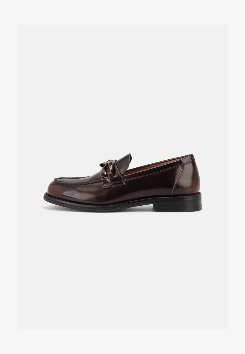 Mocassin homme en cuir marron foncé avec petit talon et mors décoratif en métal sur la empeigne, présenté en profil latéral sur fond blanc.