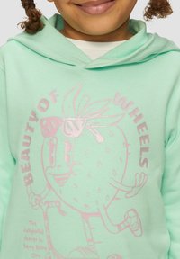 Miętowy hoodie z grafiką uśmiechniętej postaci truskawki na hulajnodze, z różowym błyszczącym tekstem i akcentami. Miękka tekstura tkaniny.