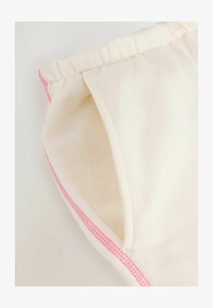 Lichtbeige shorts van zachte stof, met roze stiksels langs de naden en een elastische tailleband voor comfort.