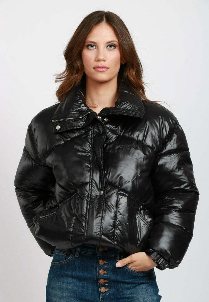 Giacca a vento nera con texture lucida e trapuntata, grande colletto, zip frontale e chiusura con bottoni a pressione; presenta tasche laterali e design accorciato.