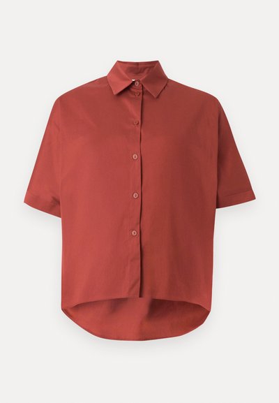Chemise à manches courtes couleur rouille avec boutons, col et ourlet légèrement plus long et arrondi à l'arrière, sur fond blanc.