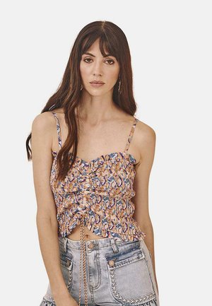 Top corto con fruncidos en un estampado floral multicolor, presenta tirantes finos y acentos de volantes. Combinado con pantalones cortos de mezclilla de cintura alta.