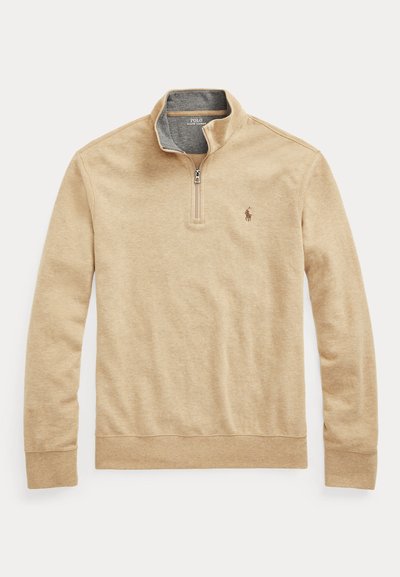 Bež majica s dolgimi rokavi, z zapenjanjem do četrtine, stoječim ovratnikom in majhnim izvezenim logotipom Polo Ralph Lauren na levi strani prsnega koša.