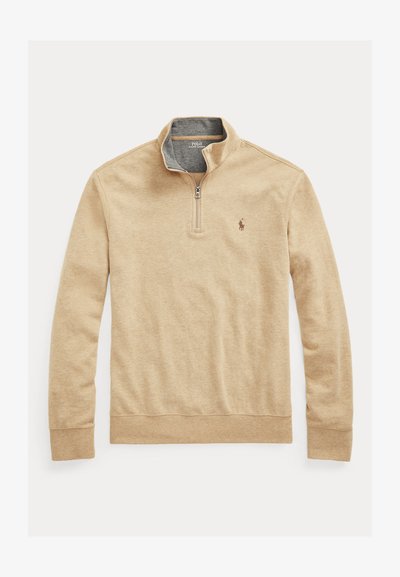 Bež majica s dolgimi rokavi, z zapenjanjem do četrtine, stoječim ovratnikom in majhnim izvezenim logotipom Polo Ralph Lauren na levi strani prsnega koša.