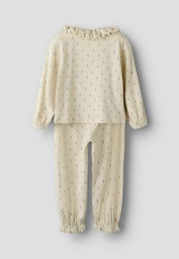 Beige geribbelde pyjama-set met een volant halslijn. De top heeft een subtiel bloemenpatroon en de broek heeft elastische boorden.