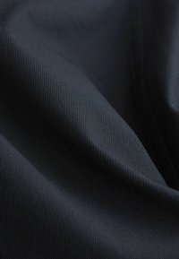 Tekstureeritud must kangas kitsaste vertikaalsete triipudega, millel on sile pind ja kerge sära, pehmete voltide ja langustega.