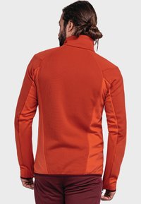 Orange fleece jacket with a high collar, textured fabric, and fitted sleeves. Includes contrasting side panels and a streamlined design.