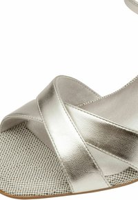 Sandal in argento con cinturini incrociati, parte superiore metallica liscia, soletta testurizzata con motivo a scacchi e suola piatta.