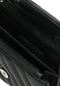 Portefeuille en cuir noir avec un design matelassé, poche zippée et fermeture à pression. Intérieur lisse avec une texture mate contrastante visible.