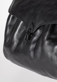 Borsa in pelle nera con una texture morbida, design plissettato e una chiusura a scatto nera prominente. Presenta una finitura liscia e lucida.