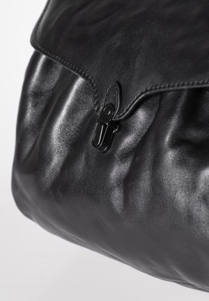 Zwarte leren tas met klepsluiting, vastgemaakt door een zwarte metalen gesp, met een close-up van gladde en gestructureerde leren oppervlakken.