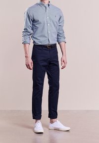 Mörkblå och vit rutig skjorta för män, matchad med marinblå byxor och vita sneakers. Långa ärmar, button-down krage och avslappnad passform.