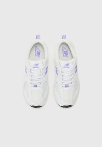 Baskets de sport blanches avec des accents violets, tige en mesh, semelle rembourrée et fermeture à lacets. Présente le logo New Balance sur les côtés et la languette.
