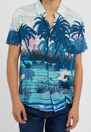 Camisa de manga corta con botones, con diseño de palmeras azules, agua y grullas blancas en un paisaje tropical.