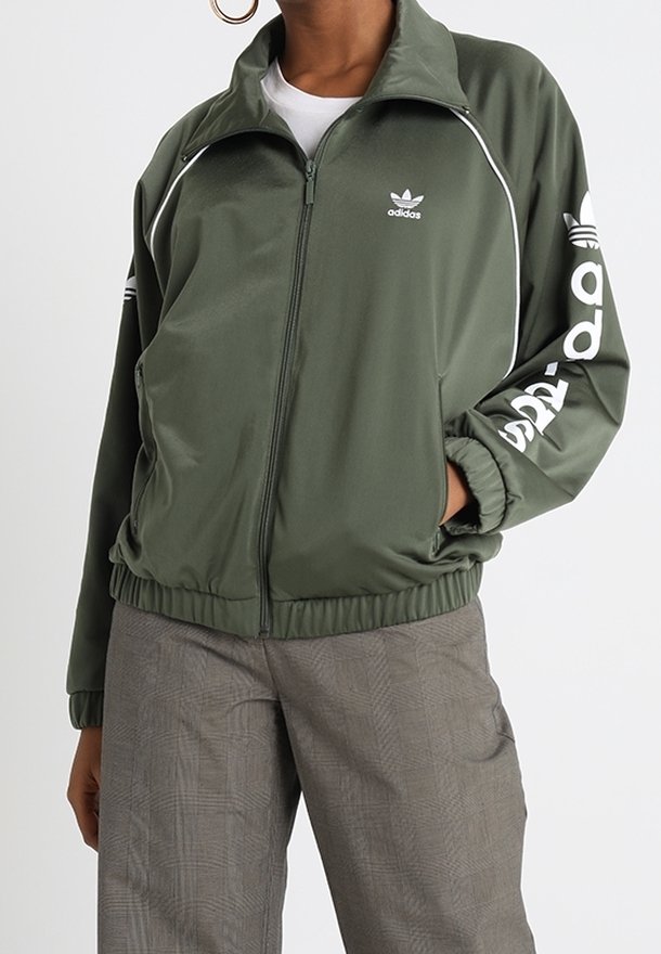 Grön polyester zip-jacka med vita detaljer, med "adidas" logotyp på vänster bröst och ned längs höger ärm. Elastisk midja.