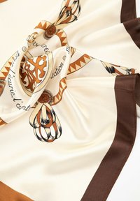 Foulard en soie avec une base crème ornée de motifs géométriques marron et or, de délicates illustrations en ligne noire et d'un éclat satiné.