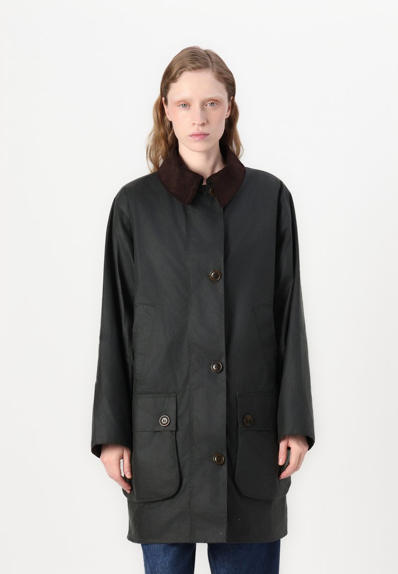 Casaco verde escuro com botões, gola em veludo cotelê castanha e dois bolsos frontais. Apresenta um corte direito e mangas longas.